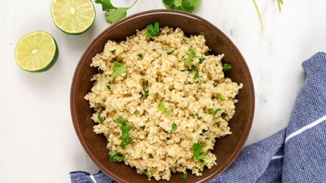 Cilantro lime quinoa in a bowl with cilantro leaves, lime zest, garlic, and onion.