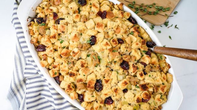 Healthy cornbread sausage stuffing with dried cranberries and thyme in a baking dish.