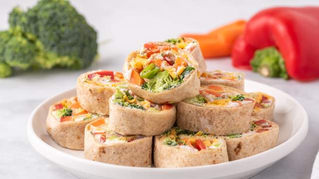 Cream cheese pinwheel with chopped vegetables and ranch seasoning cut into slices on a plate.