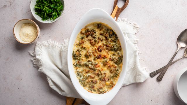 Creamed kale with tender kale cooked with cream cheese, milk, and Parmesan cheese in a white baking dish,