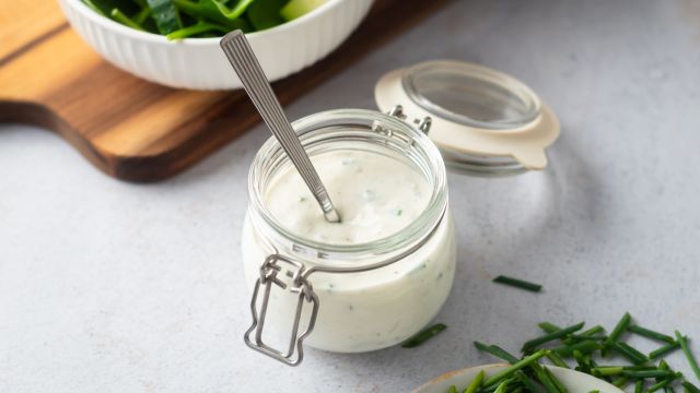 Creamy gorgonzola dressing with chunks of gorgonzola cheese, Greek yogurt, chives, and buttermilk in a small glass jar.