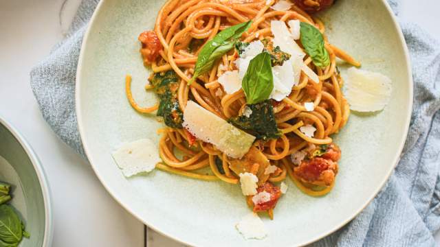 Creamy tomato mushroom and spinach pasta on a plate with whole grain pasta, creamy sauce, spinach, mushrooms, and parmesan cheese.