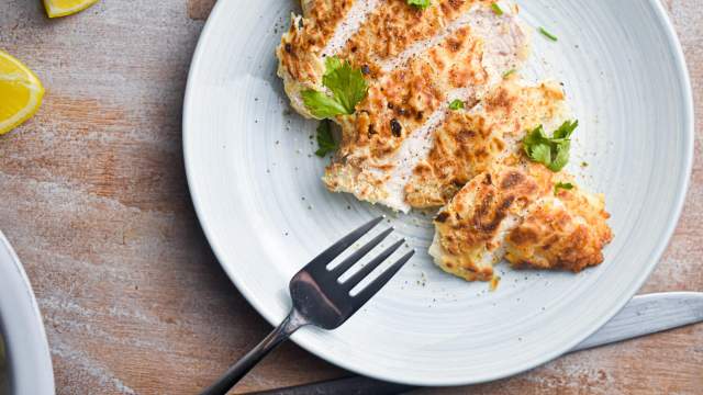 Buttermilk chicken breast cooked until crispy and sliced on a plate with lemon.