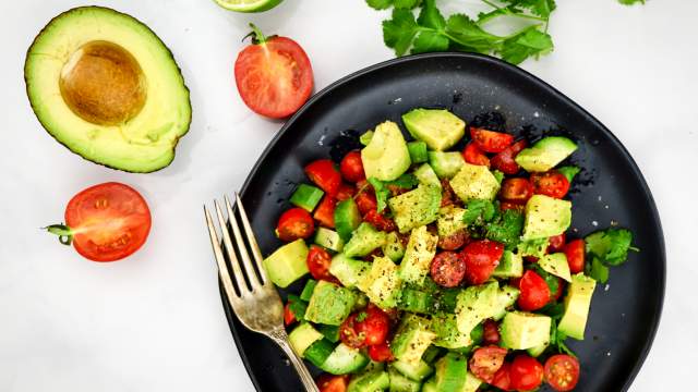 Cucumber avocado salad with tomatoes in a wooden bowl.