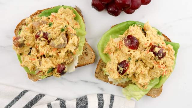 Curry tuna salad on whole wheat toast with lettuce and red grapes.