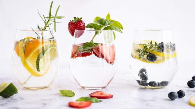 Detoz water in a glass with lemon, lime, and orange slices with rosemary sprigs.