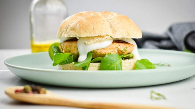 Dill Salmon Burgers with yogurt sauce and dressing on a whole wheat bun.