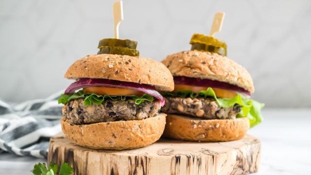 Double bean burgers made with black beans, white beans, cilantro, onion, and spices cooked and served on wheat buns with vegetables.