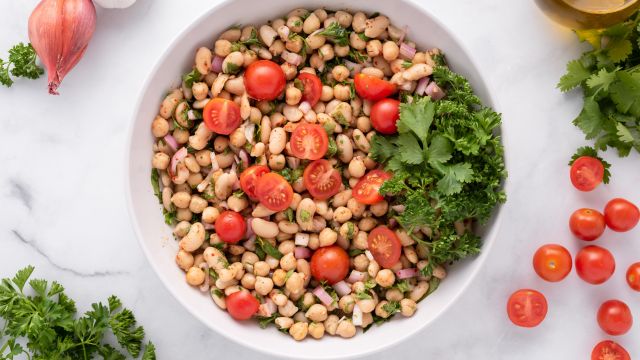 Easy bean salad with chickpeas, white beans, shallots, cherry tomatoes, and fresh herbs in a bowl.