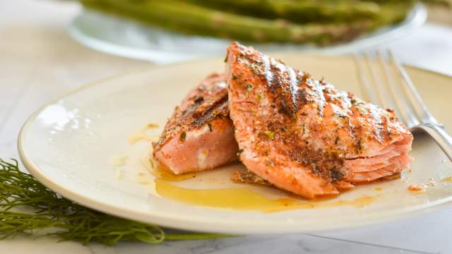 Grilled salmon with a Cajun spice rub on a plate with asparagus and salad./