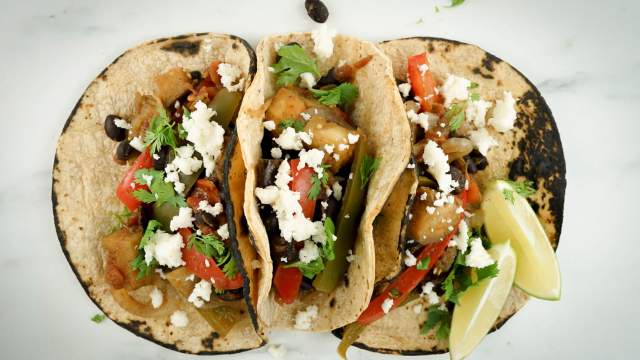 Baked eggplant fajitas with peppers and onions in corn tortillas with queso fresco.