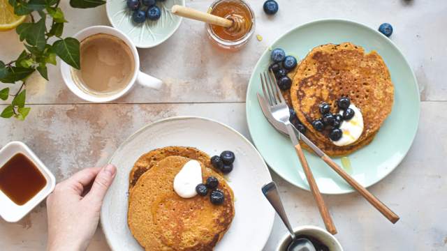 Low carb Flaxseed meal pancakes stacked on a plate with berries, yogurt, and a drizzle of syrup.