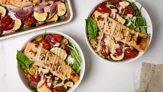 Roasted Garlic Salmon and Vegetable Farro Bowls with a garlic drizzle sauce in two bowls.