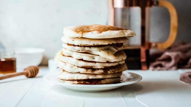 Greek yogurt stacked on a plate with maple syrup and coffee on the side.