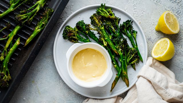 Garlic grilled broccolini served on a plate with fresh lemon and garlic aioli 