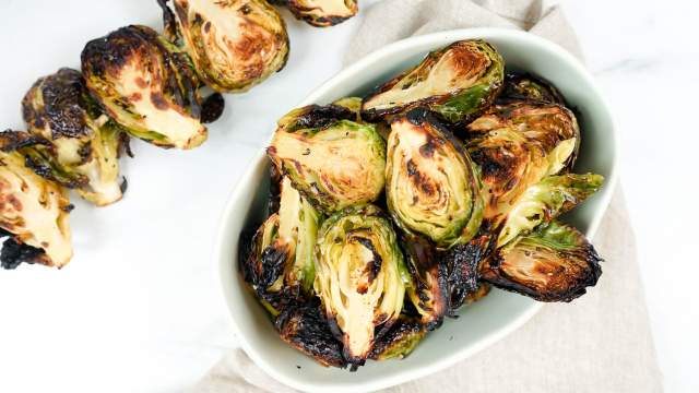 Grilled Brussel Sprouts on a skewer and in a bowl with grill marks.