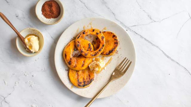 Grilled butternut squash on a plate with chili powder, cinnamon, salt, pepper, and butter on the side.