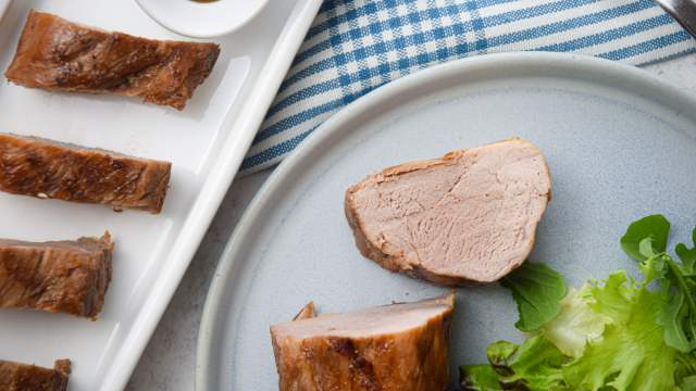 Grilled hoisin pork tenderloin with an Asian marinade on a plate with greens.