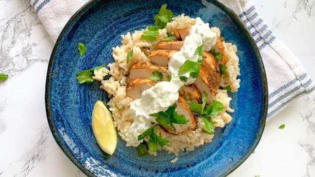 Grilled lemon chicken breast with tzatziki on a bed of rice. 