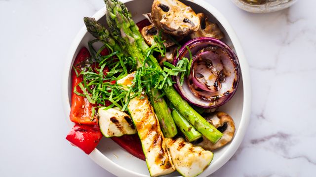 Grilled marinated vegetables with balsamic marinade in a white bowl.