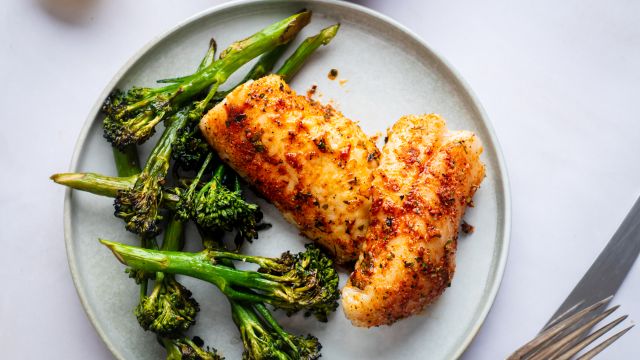 Grilled red snapper with homemade spice rub on a plate with grilled broccoli.