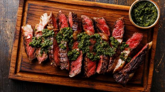 Grilled sirloin steak on a cutting board with chimichurri.