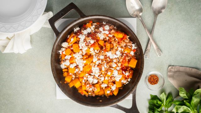 Ground turkey and butternut squash skillet with tomatoes and fresh herbs in a ceramic baking dish.