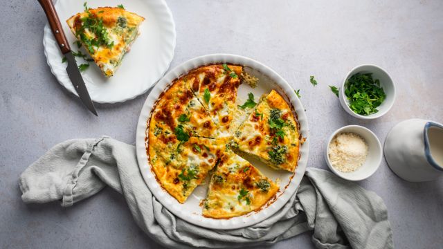 Ham and cheese frittata with broccoli cooked in a pie dish with a slice cut on the side. 