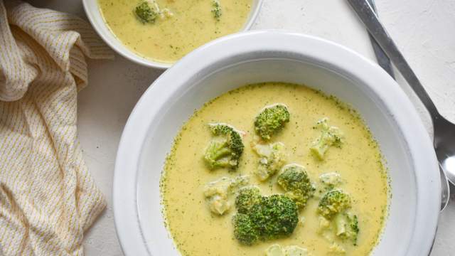 Healthy Broccoli Cheese Soup with broccoli florets, cheddar cheese, and a creamy broth in two bowls.