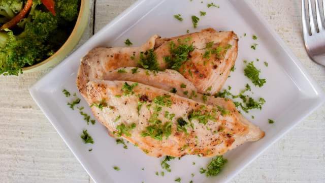 Herb chicken breast with an herb spice rub on a plate with fresh parsley.