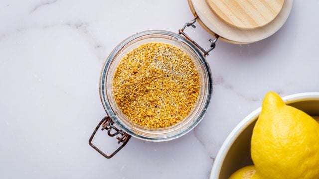 Homemade lemon pepper seasoning with dried lemon zest, black pepper, kosher salt, garlic powder, and onion powder in a glass jar.