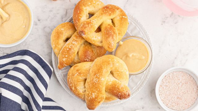 Homemade soft pretzels made with two ingredient dough and sprinkled with salt on a white plate.