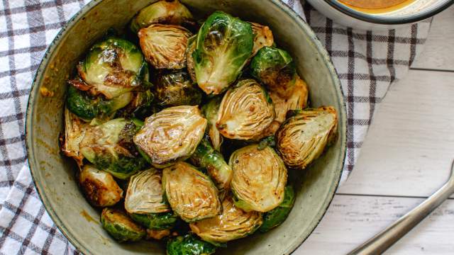Honey mustard Brussels sprouts in a bowl with the sauce in a small bowl on the side.