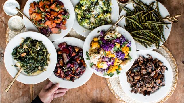 Roasted vegetables including broccoli, cauliflower, mushrooms, beers, and bok choy on a wooden table.