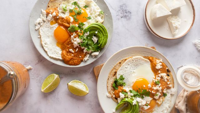 Huevos rancheros with sunny side up eggs served on corn tortillas with ranchero sauce, avocado, and cheese.