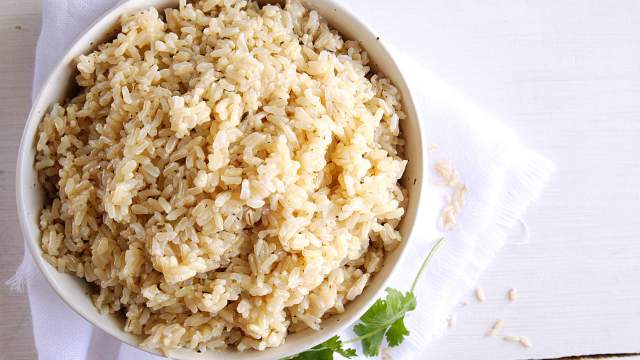 Instant pot brown rice in a bowl with small flecks of dried parsley.