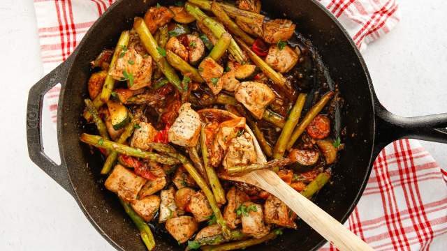 Italian chicken and vegetable skillet in a pan with chicken breast, asparagus, zucchini, parsley, and fresh lemon.