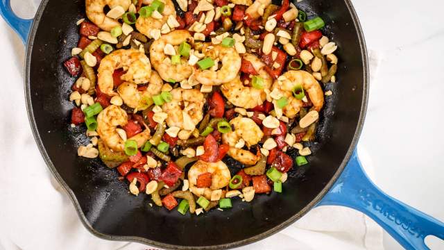 Kung Pao Shrimp with peanuts, celery, red peppers, and green onions in a skillet.