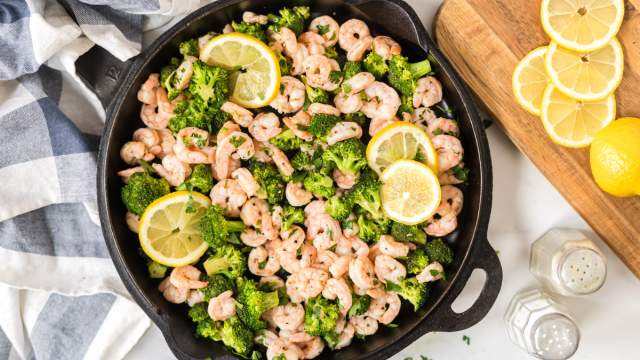 Lemon pepper shrimp and broccoli in a cast iron skillet with garlic, shrimp, and brocoli florets.