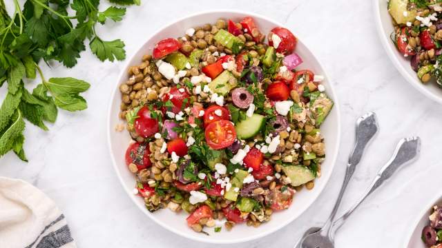 Easy lentil salad with Mediterranean flavors including olives, feta cheese, tomatoes, cucumbers, and fresh herbs in a bowl.