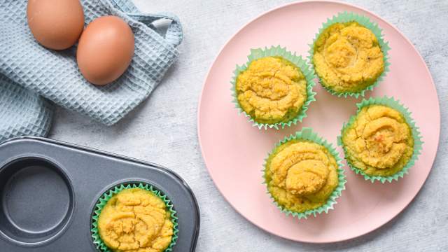 Low carb coconut muffins made with coconut flour on a pink plate with a muffin tin on the side.