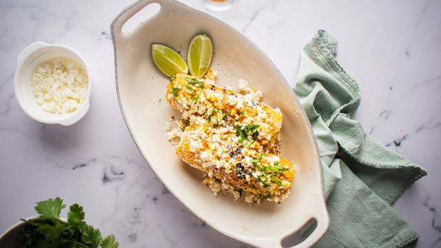 Mexican street corn on the cob with mayo, queso fresco, lime, cilantro, and chili powder.