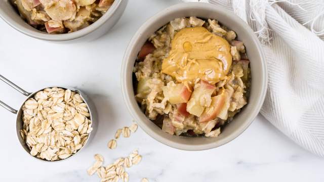 Microwave apple oatmeal with peanut butter and cooked apples in a bowl with cinnamon.