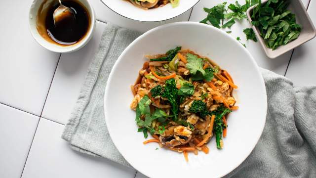 Moo shu vegetables with eggs and hoisin sauce served in a bowl with cabbage, broccoli, and mushrooms.