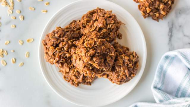 No bake peanut butter oatmeal cookies on a plate with loose oats on the side. 