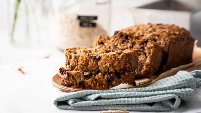 Oatmeal banana bread with chocolate chips sliced on a plate with a blue cloth napkin.