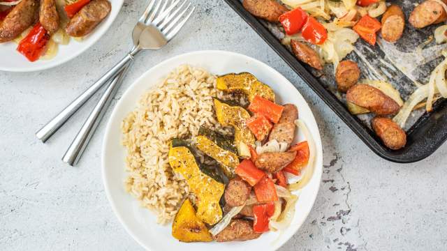 One pan sausage and acorn squash with bell peppers and onions on a plate with brown rice.