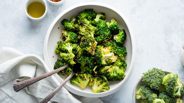 Pan fried broccoli with garlic, olive oil, and red pepper flakes in a white bowl.