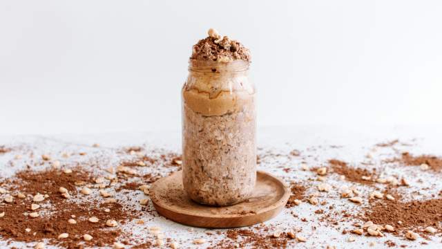 Peanut butter cup overnight oats in a glass jar with peanut butter and cocoa powder.