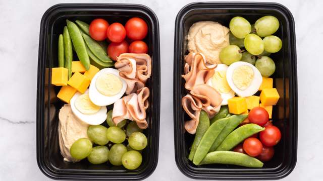 Copycat Starbucks Protein Snack Box in two containers with hard boiled eggs, hummus, vegetables, fruit, and deli turkey.